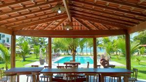 a patio with tables and chairs and a swimming pool at Bangalô 7b Praia de Guaratiba in Prado