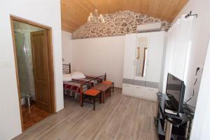 Una pequeña habitación con una cama y un televisor. en Poolhouse Wowox, en Grižane