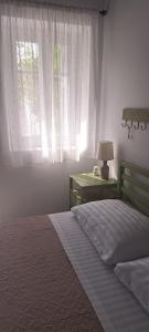 a bedroom with a bed and a lamp and a window at Sweet Home Kini in Kinion