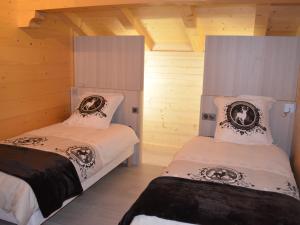 zwei Betten in einem Zimmer mit Holzwänden in der Unterkunft Chalet moderne 5 étoiles pour 10 pers. avec parking privé - FR-1-467-93 in Le Grand-Bornand