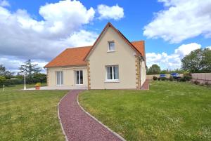 a house on a grassy yard with a path at Villa DES COEURS NORMANDS in Pirou