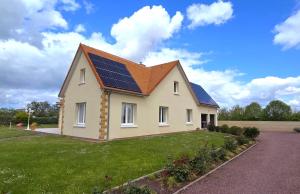 a house with solar panels on the roof at Villa DES COEURS NORMANDS in Pirou