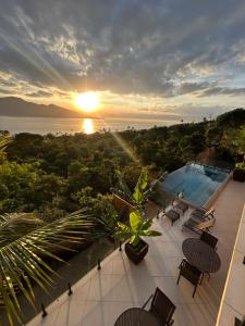 a sunset on the roof of a house with a pool at Maluhia Ilhabela 4 in Ilhabela