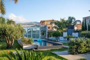 a garden with a swimming pool and a house at Hotel La Martinica in Ficarazzi