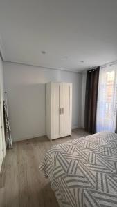 an empty bedroom with a bed and a cabinet at vivienda turística Irún in Irún