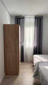 a bedroom with a bed and a wooden cabinet next to a window at vivienda turística Irún in Irún