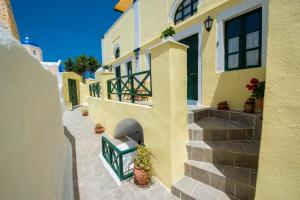 a yellow building with stairs and potted plants on it at Christos Apartments Oia in Oia
