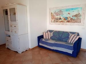 a blue couch next to a cabinet and a painting at The pool house - Il Gabbiano in Palau