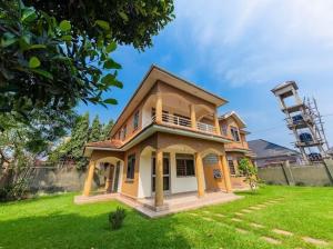 a small house in a yard with a green lawn at L&R Homes in Kampala