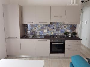 a kitchen with white cabinets and a stove top oven at A casa di Azzurra in Roseto degli Abruzzi