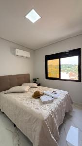 a bedroom with a large bed with a window at Apto Flor de Romã - 2 Quartos, Apto todo climatizado, à 150m do Parque Termal! in Piratuba +14 photos