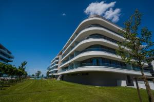 un grand bâtiment blanc avec une pelouse verte devant lui dans l'établissement MyFlat Wave 31 Suite, à Siófok
