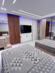 a bedroom with a large bed and a flat screen tv at Comfy 2-Bedrooms Apartment in Cairo Sheraton airport in Cairo