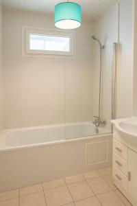 a white bathroom with a tub and a sink at Appartement spacieux de 92m2 in Brest
