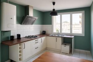 a kitchen with green walls and white cabinets and a sink at Appartement spacieux de 92m2 in Brest