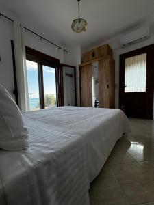 a large white bed in a room with large windows at Agnanti - Seafront Home with Aegean Sea View in Loutrá Elevtherón +30 photos