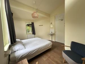 a bedroom with a white bed and a chair at Plaats De Kleine Aarde in Boxtel +9 photos