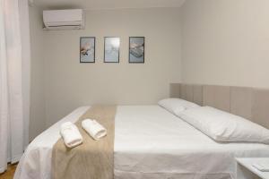 a white bedroom with a bed with towels on it at Conforto no Centro de Maringá MC11 in Maringá