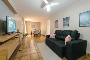a living room with a green couch and a flat screen tv at Conforto no Centro de Maringá MC11 in Maringá