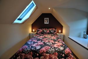 a bedroom with a bed with a floral bedspread and a window at 54 On the Rocks- characterful coastal cottage in Anstruther