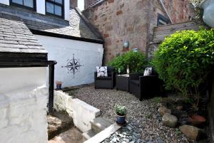 a garden with couches and plants next to a building at 54 On the Rocks- characterful coastal cottage in Anstruther