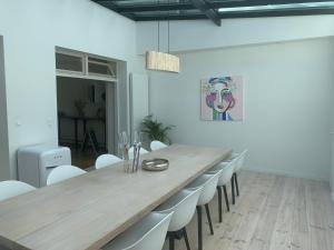 a dining room with a long table and white chairs at Entre Deux Eaux in Lanaken