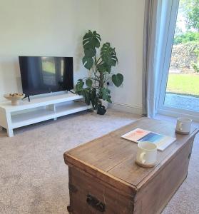 a living room with a tv and a coffee table at Fig Tree Cottage in North Cornelly