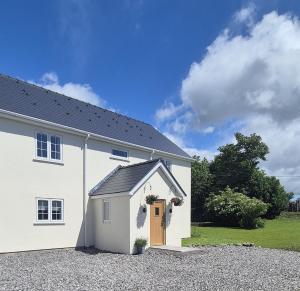 a white house with a brown door in a driveway at Fig Tree Cottage in North Cornelly