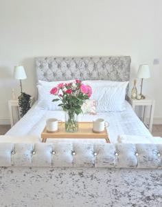 a bed with a vase of flowers on a table at Fig Tree Cottage in North Cornelly