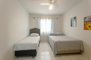 a bedroom with two beds and a window at Apartamento Econômico - AL09 in Maringá +11 photos