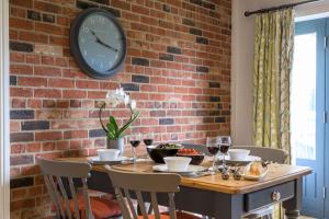 einen Tisch mit Stühlen und eine Uhr an einer Ziegelmauer in der Unterkunft Beech Cottage in Boston + 10 Fotos