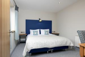 une chambre avec un grand lit avec une tête de lit bleue dans l'établissement Elm Cottage, à Boston