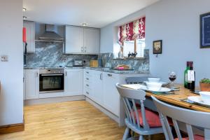 une cuisine avec des armoires blanches et une table en bois dans l'établissement Elm Cottage, à Boston