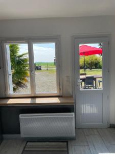 a room with two windows and a table with an umbrella at La Colinière Sambin in Sambin