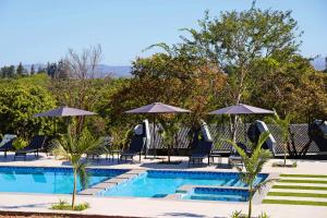 a swimming pool with chairs and umbrellas at Siyabonga Boutique Lodge in Nelspruit