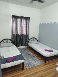 two twin beds in a room with a window at Aisyah Homestay Arau in Arau +19 photos