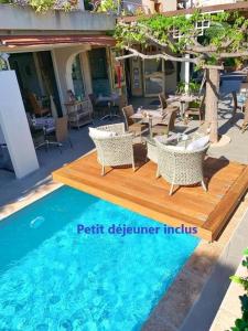 a patio with tables and chairs and a pool at Hôtel Beau Soleil in Le Lavandou