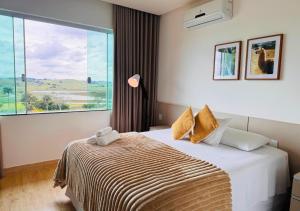 a bedroom with a bed and a large window at Hotel Chalé Capitólio in Capitólio