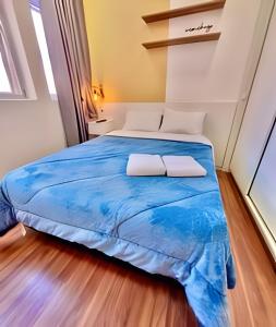 a bedroom with a large bed with blue sheets at Estúdio Elegante, bem no centro - Ar quente/frio in Curitiba