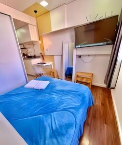 a room with a blue bed and a kitchen at Estúdio Elegante, bem no centro - Ar quente/frio in Curitiba