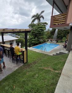 a group of people sitting at a table by a pool at El Encanto Del Yunque in Jayuya