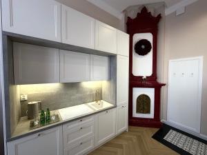 a kitchen with white cabinets and a red clock at Suites & Premium Apartments Słowackiego in Kielce
