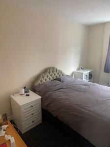a bedroom with a bed with a white nightstand and a bed sidx sidx sidx at Aylstone Gem in Leicester