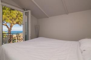 une chambre avec un lit blanc et une grande fenêtre dans l'établissement Sweet Cottage Retreat 350m from the sea by Zantewize, à Psarou