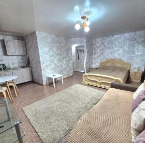 a living room with a bed and a kitchen at Однокомнатная на улице Алии Молдагуловой in Uralsk