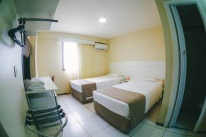 圣路易斯Soft Win Hotel São Luís的有两张床和一台电视的酒店房间