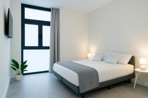 a white bedroom with a bed and a window at Formidable Apartments in Valencia