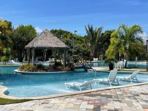 a swimming pool with chairs and a gazebo at Iloa Flat resort Apt 202 bloco i in Barra de São Miguel