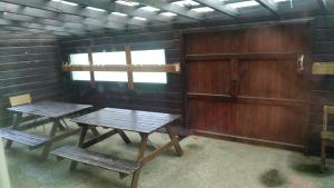 zwei Tische und Bänke in einem Raum mit Holzwänden in der Unterkunft Haus Vinzenz Amel in Amel
