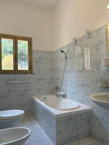 a bathroom with a tub and a toilet and a sink at Affittacamere Belvedere - Posada in Posada